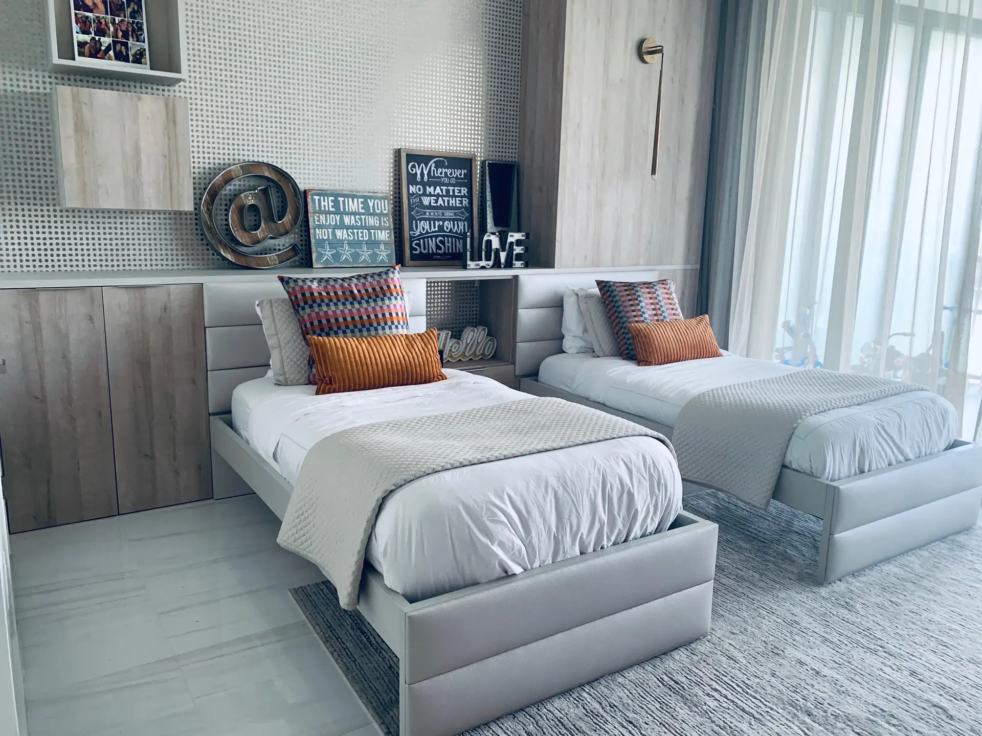 Bedroom with two upholstered beds, a shared channel-tufted headboard wall, and light-wood built-in paneling
